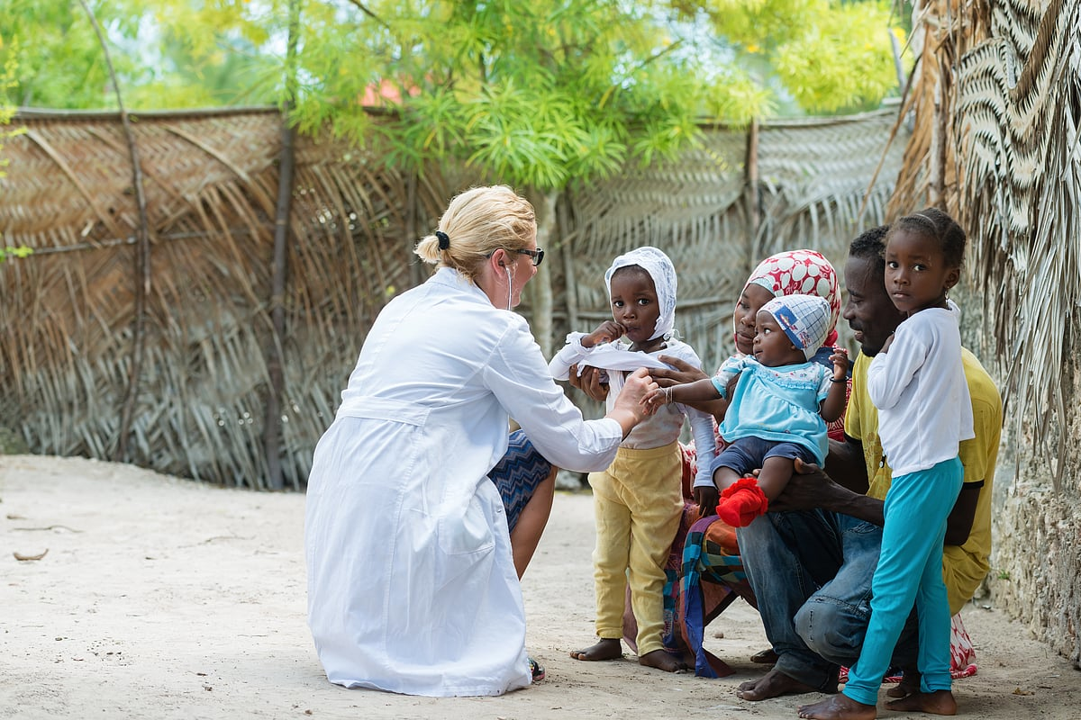 Foreign aid worker engaging with children in a rural African community during a health or humanitarian outreach